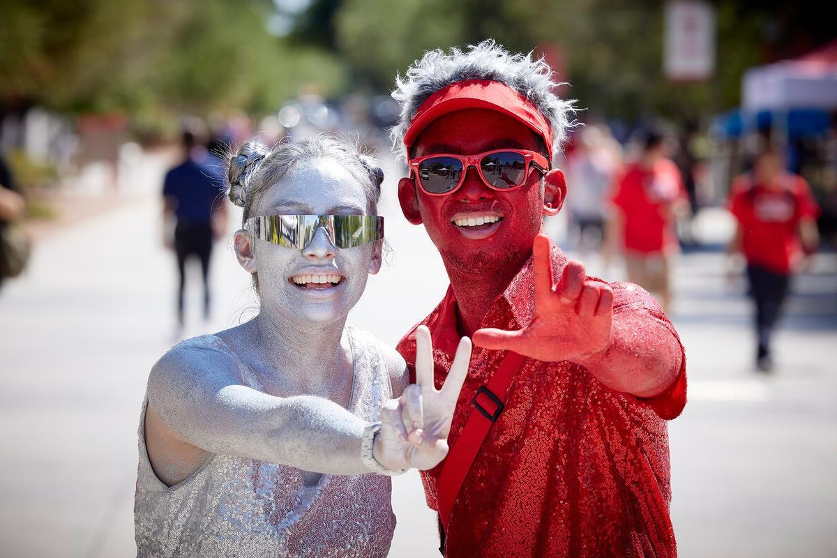 Two students with scarlet and gray body paint, make L.V. sign with their hands